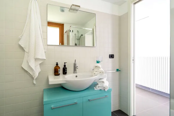 Bathroom basin on a turquoise vanity unit, with a mirror above