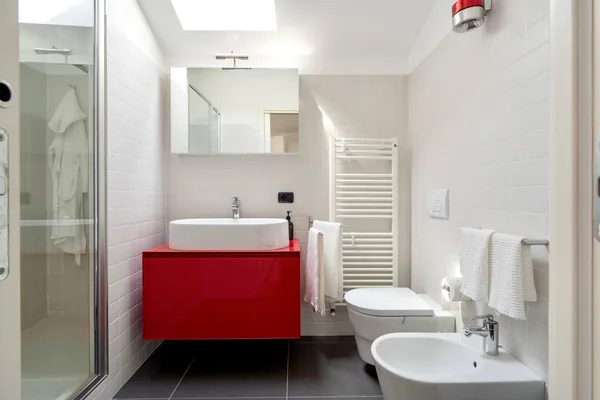 Bathroom with a walk-in shower, red vanity unit, WC and bidet
