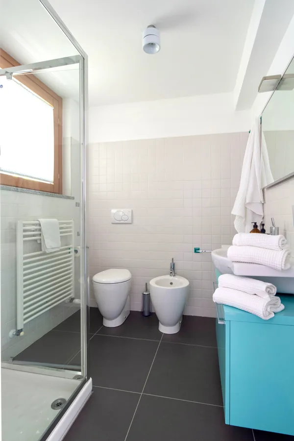Second bathroom with a shower, turquoise vanity and folded towels
