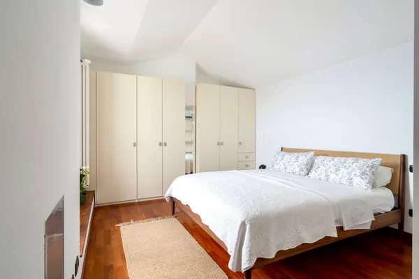 Bedroom with a wooden bed, white linen and full-height fitted wardrobes