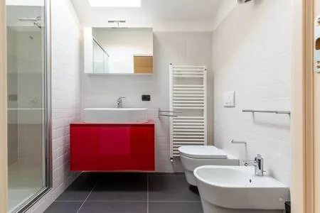 Ground-floor bathroom with a walk-in shower, red vanity unit and bidet