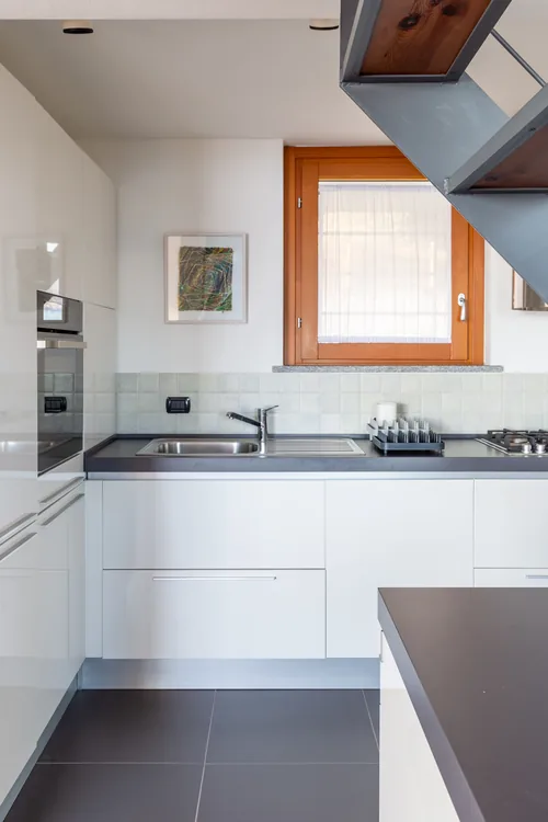 Kitchen with extractor hood, sink and dark tiled floor