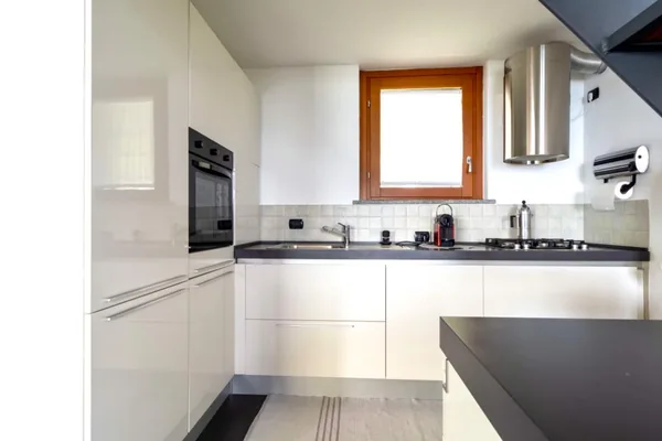 White fitted kitchen with a gas hob, extractor hood and a window over the counter