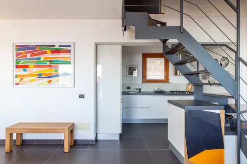 Open-plan kitchen and stairs with a colourful abstract painting on the wall