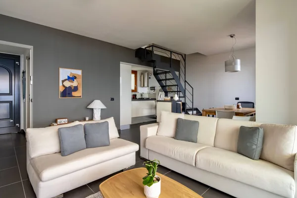 Wide view of the living room with two sofas and the open steel staircase to the upper floor