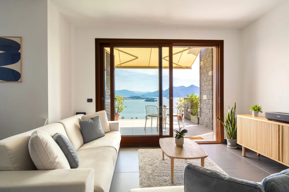 Living room with pale sofas and sliding doors open onto the terrace and the lake