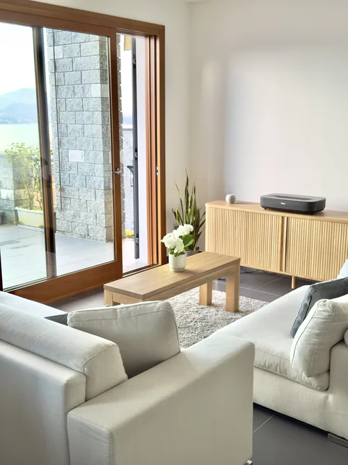 Bright living room with pale sofas, a wooden console and doors to the terrace