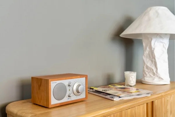 Sideboard detail: a wooden radio, a sculptural table lamp and a stack of magazines