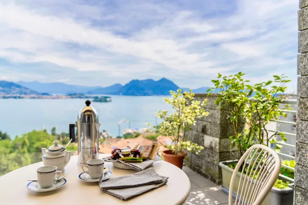 Breakfast laid on the terrace table, coffee pot and cups against the lake view