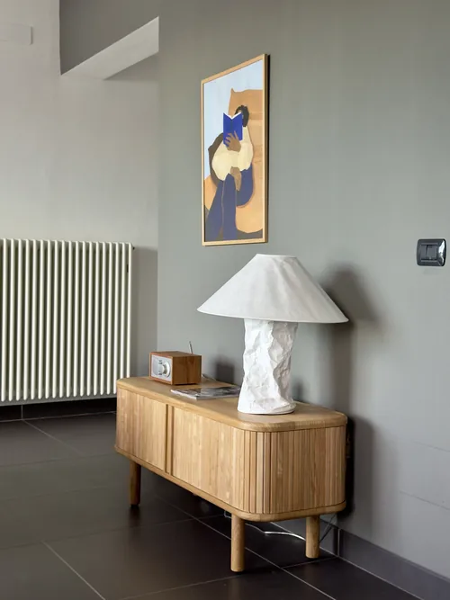 Wooden console with a textured table lamp and framed artwork above it