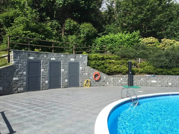 Poolside terrace with stone changing rooms, backed by woodland