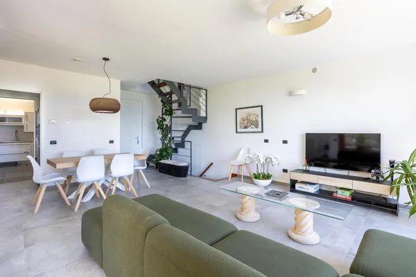 Dining table with white chairs beside the living area and the staircase