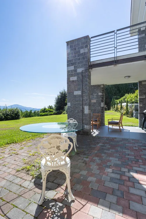 Garden terrace with a table beneath the villa's balcony, facing the lake