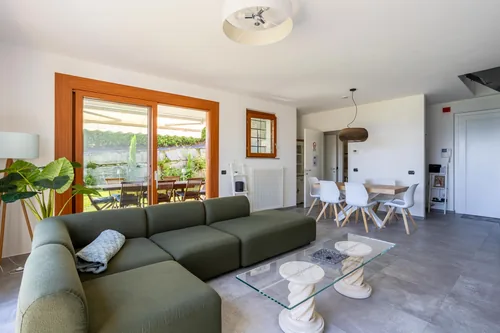 Living and dining area with green sofa, glass coffee table and doors onto the veranda