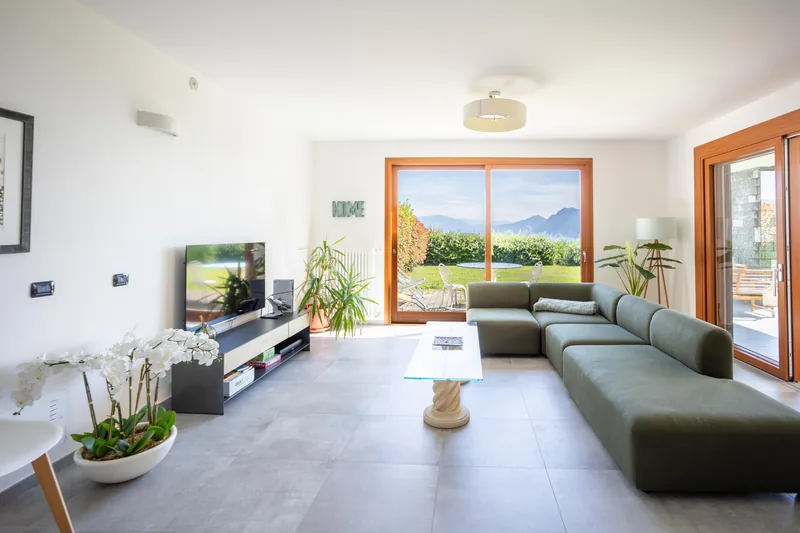 The villa's open-plan living room with a green modular sofa and doors onto the garden