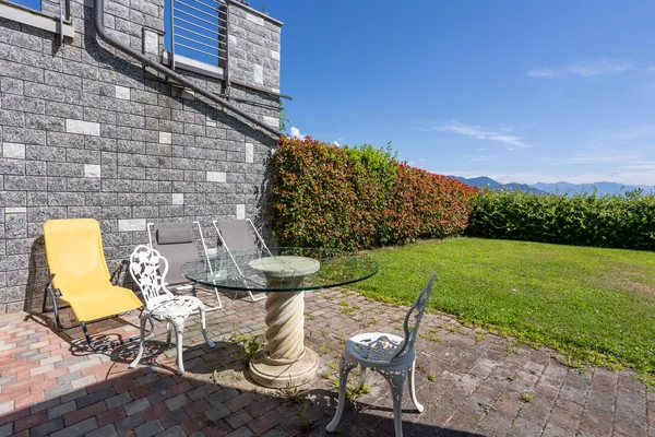 Private lawn garden with a sun lounger, table and chairs, hedged for privacy