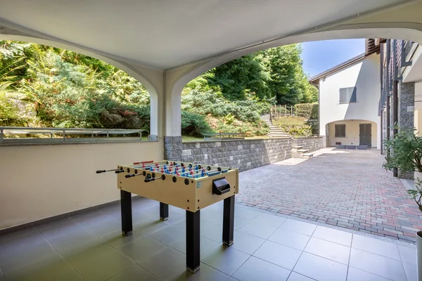 Table-football table under the villa's arched portico, open to the garden